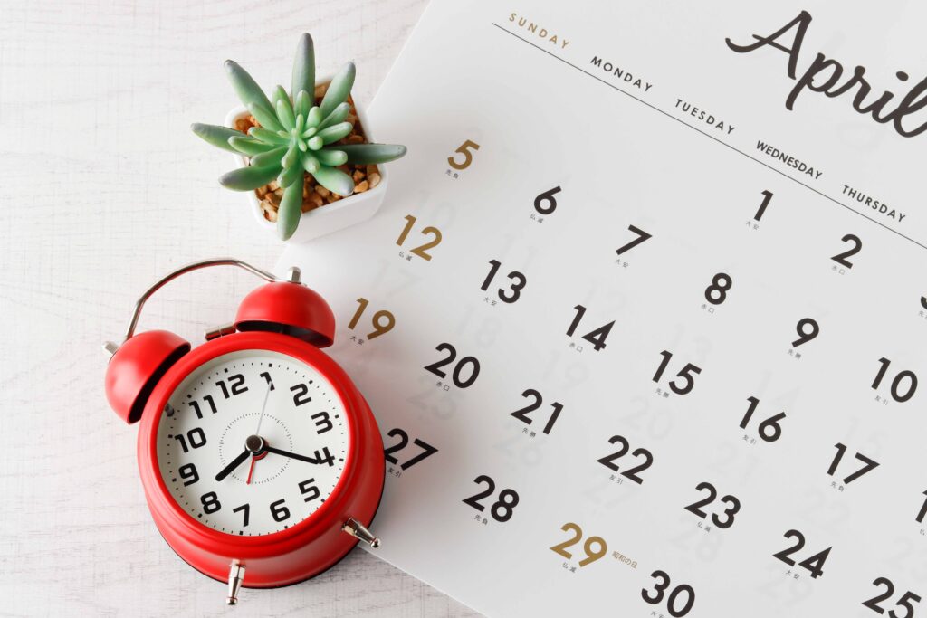 カレンダーと赤い目覚まし時計、植物が置かれている