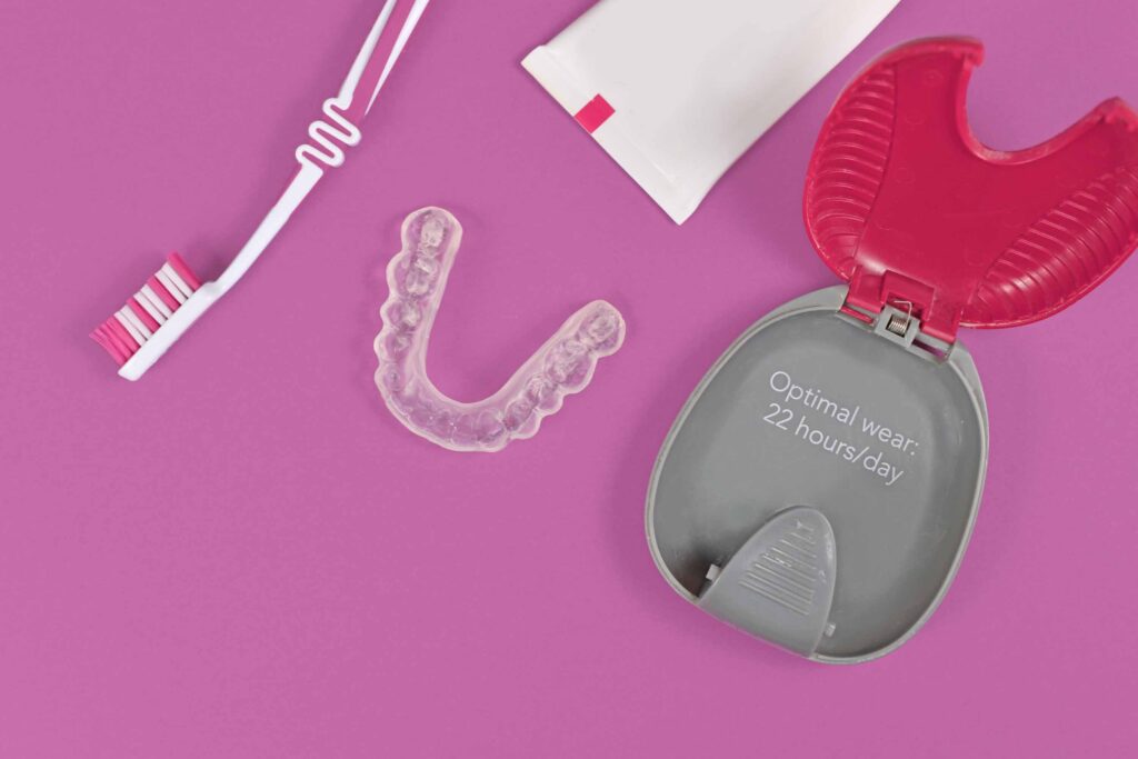 歯ブラシ・マウスピース・マウスピースケース・歯磨き粉がピンクの台に置かれている