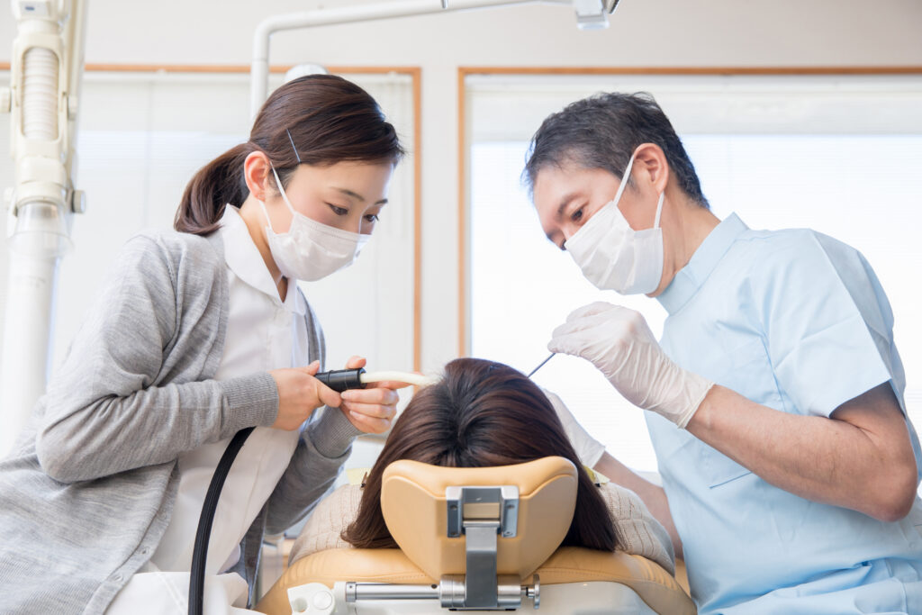 歯医者と歯科衛生士が患者の口内を治療している