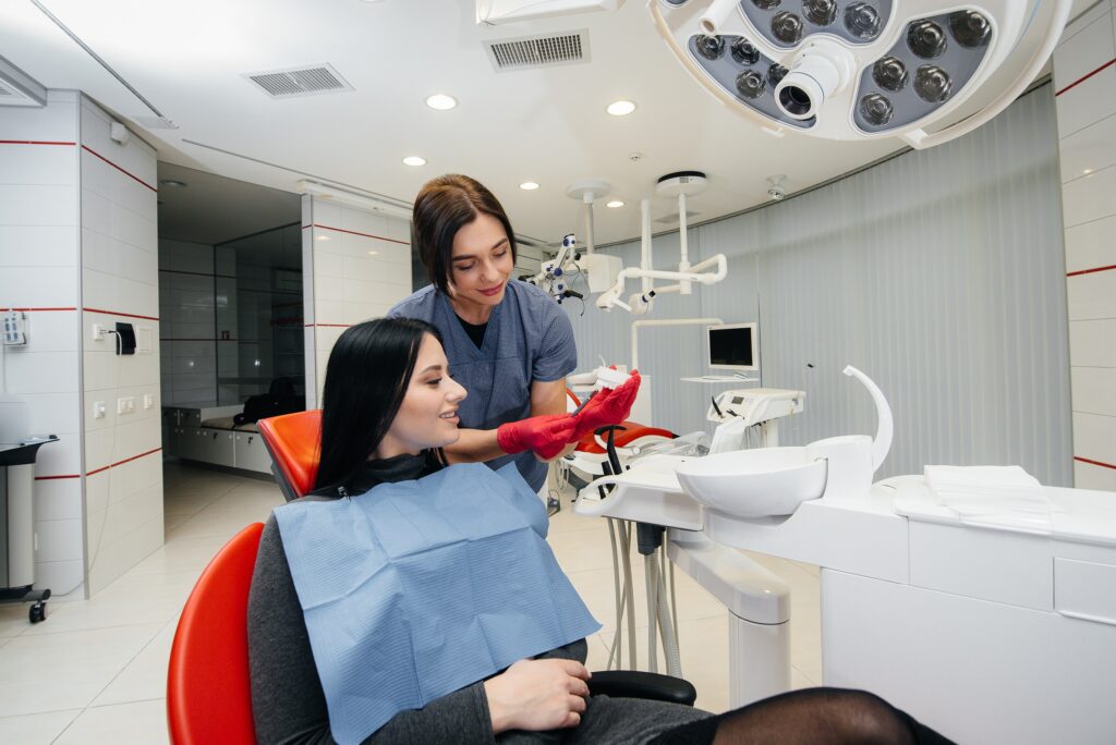 歯科の治療室で患者に歯の模型を使いながら説明する医師