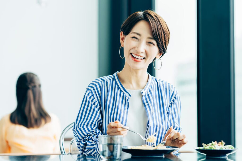 割れたセラミックの歯を治療し笑顔で食事を楽しむ女性