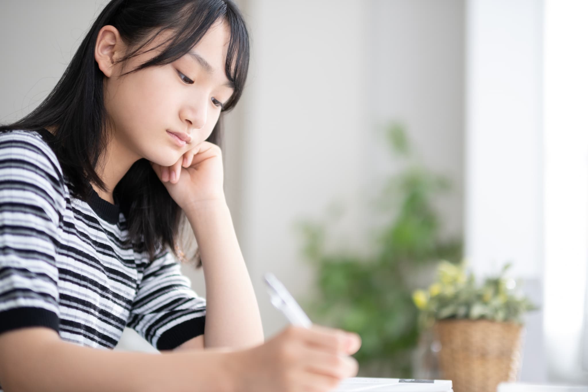 すきっ歯の原因の一つである頬杖をつく女性