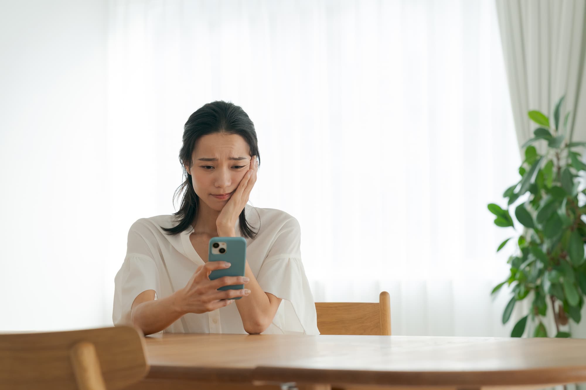 保定期間中のトラブルを不安そうにスマホで調べる女性