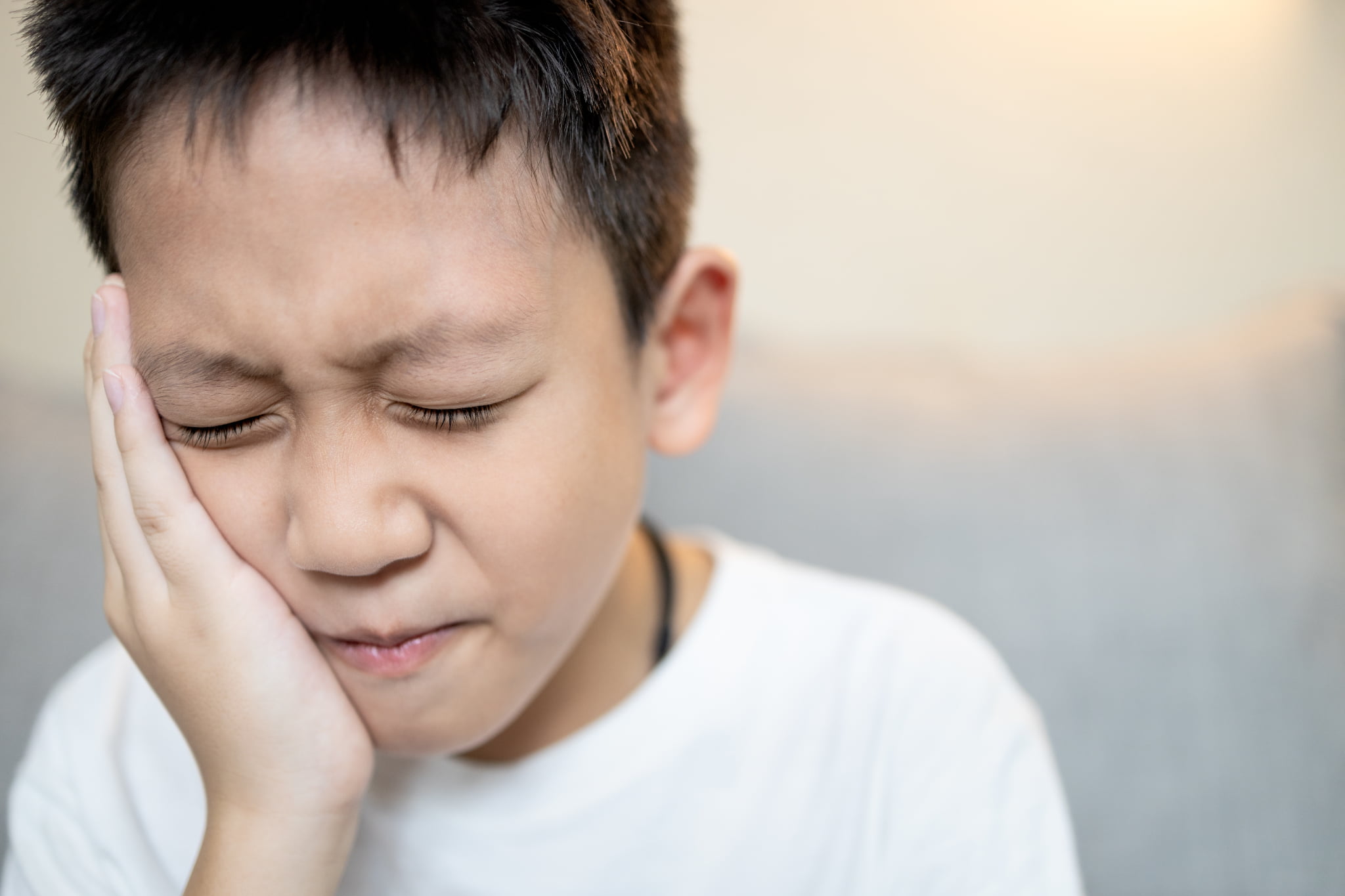 歯肉炎が痛くて頬をおさえる子ども