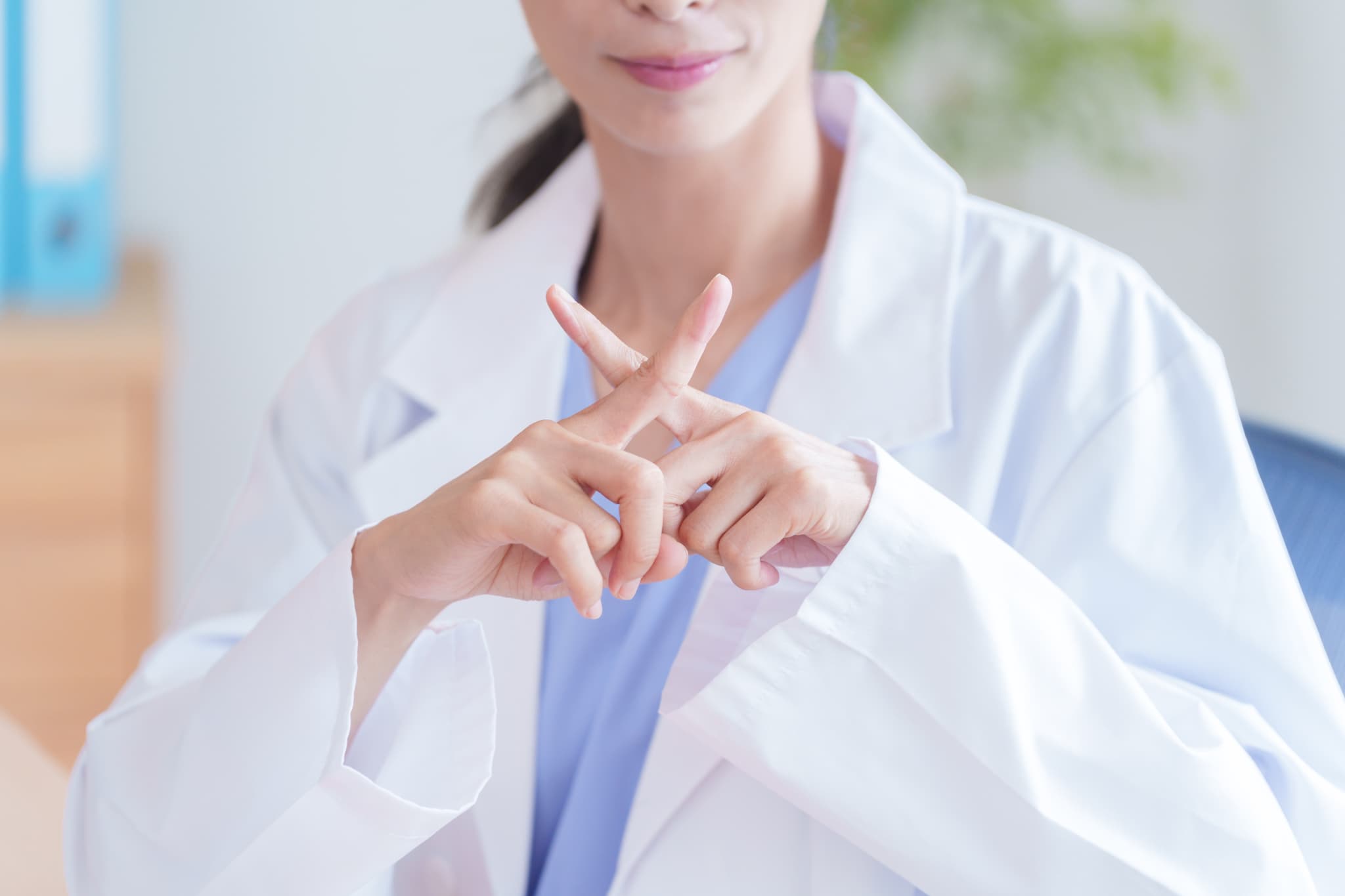 指でバツを作る歯科医師