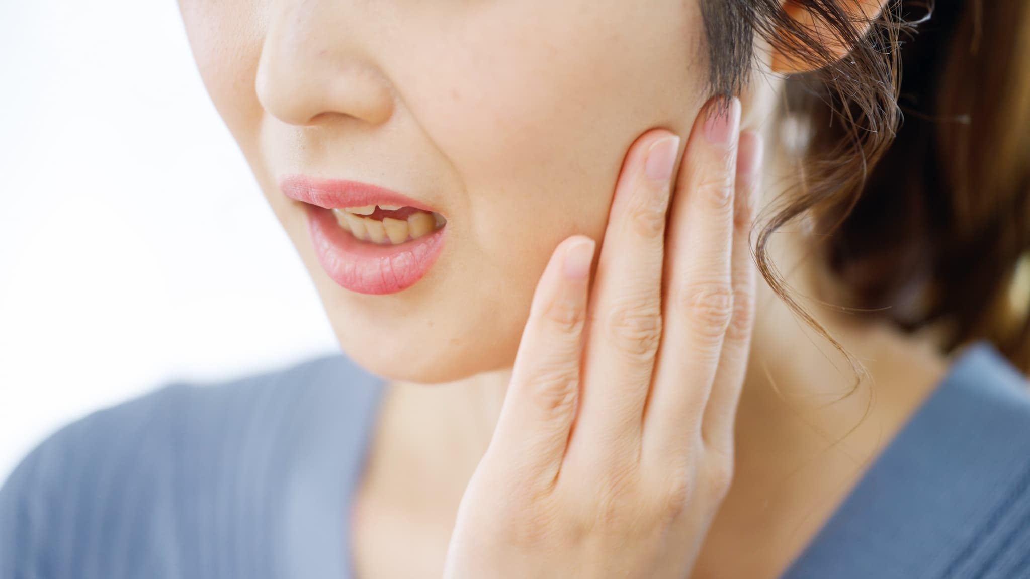 顎関節を手で触る女性