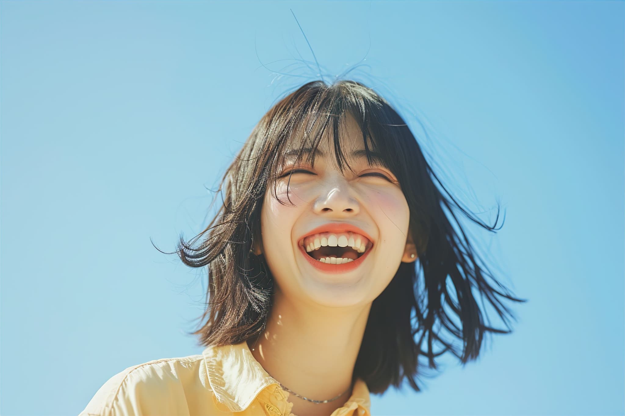 青空の下で笑う女性
