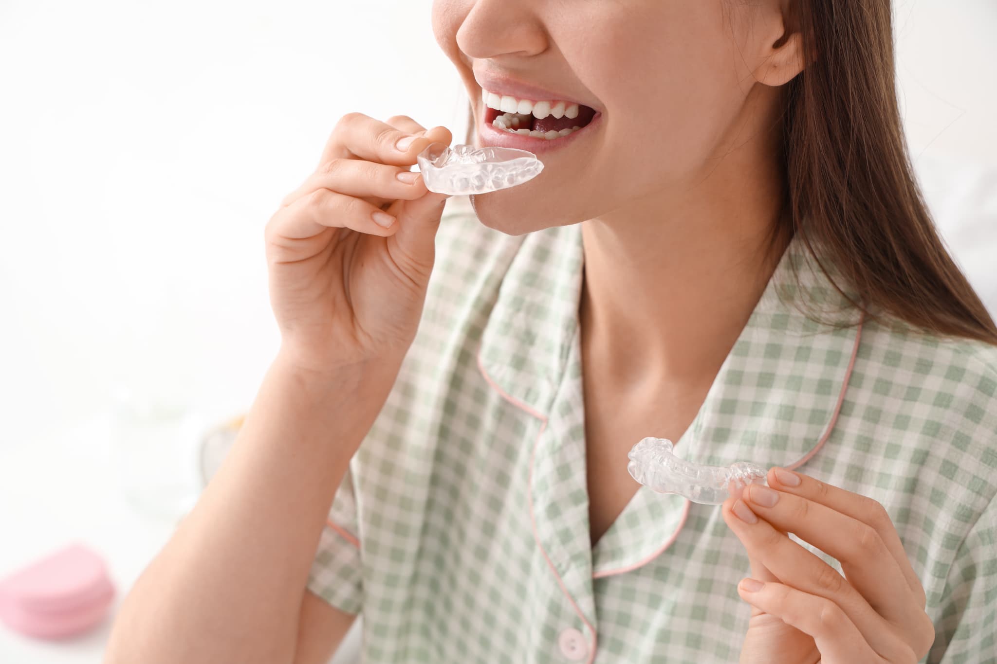 夜にマウスピースを装着するパジャマ姿の女性