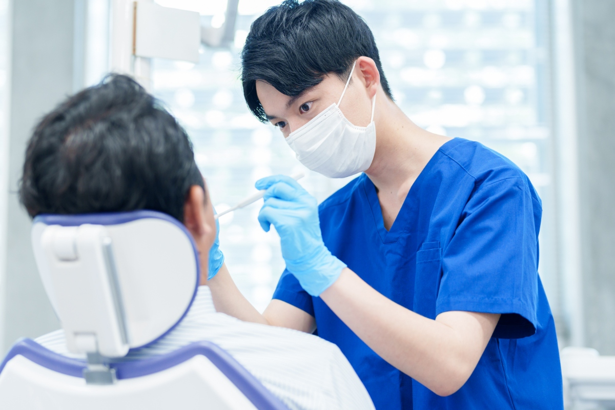 銀歯の下にできた虫歯を治療している歯科医師